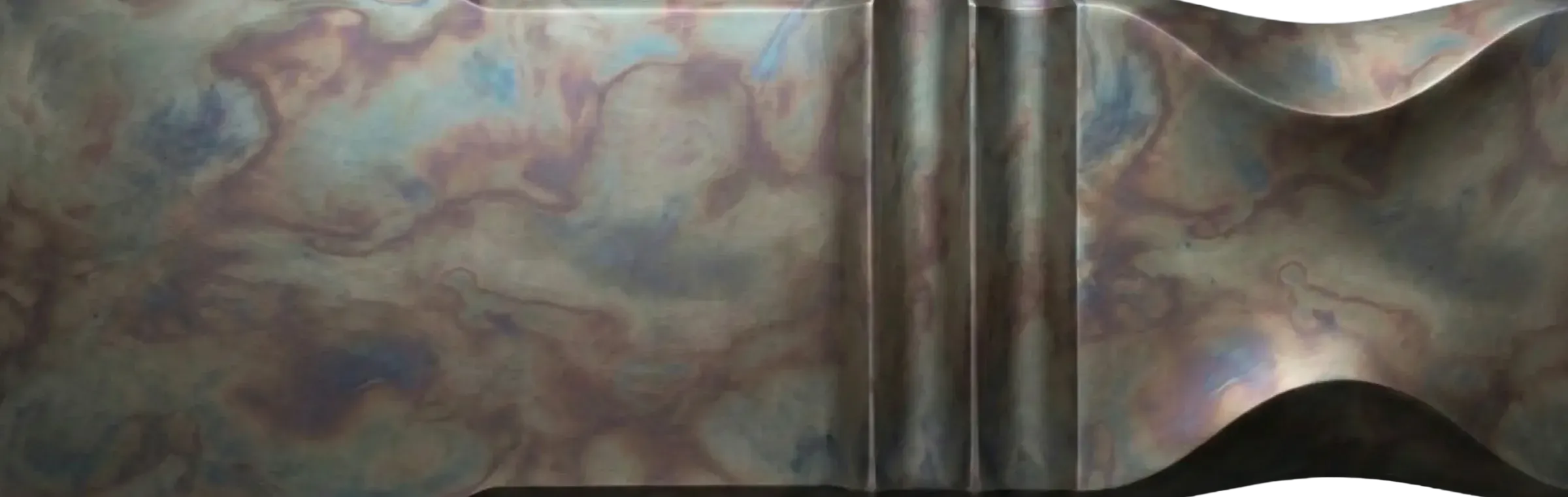 Acid Patina Zinc finish sample by Modulux with layered blue, green, violet, brown, and grey patina over sculpted architectural geometry.